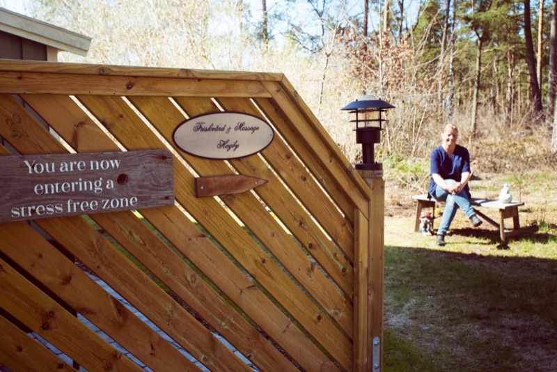 Trägrind med skylten ”You are now entering a stress free zone”, och en person som sitter på en bänk bakom den